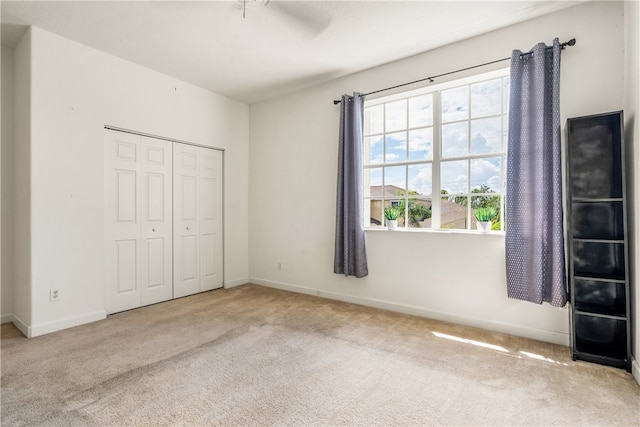 unfurnished bedroom featuring ceiling fan, a closet, and light colored carpet