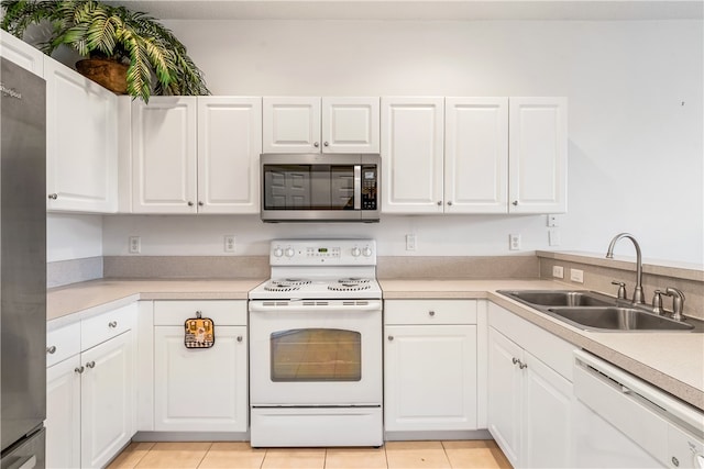 kitchen with appliances with stainless steel finishes, light tile patterned floors, white cabinetry, and sink