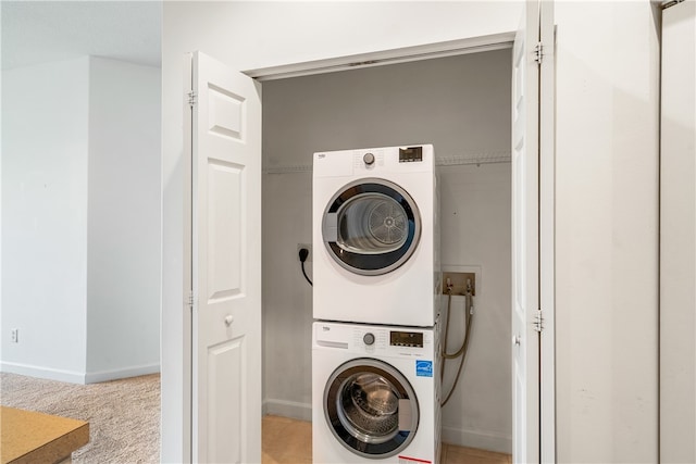 laundry area featuring light colored carpet and stacked washer / drying machine