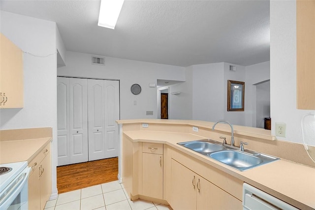 kitchen featuring light tile patterned flooring, sink, white appliances, kitchen peninsula, and a textured ceiling