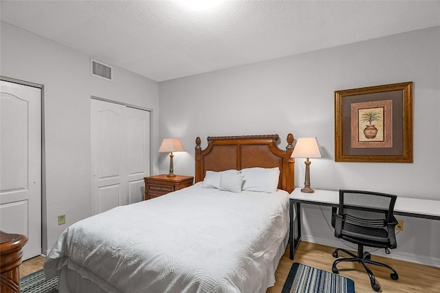 bedroom featuring two closets and light hardwood / wood-style flooring