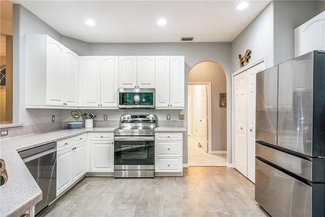 kitchen with white cabinetry, stainless steel appliances, and light hardwood / wood-style flooring