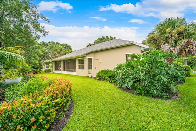 rear view of property featuring a lawn and a sunroom