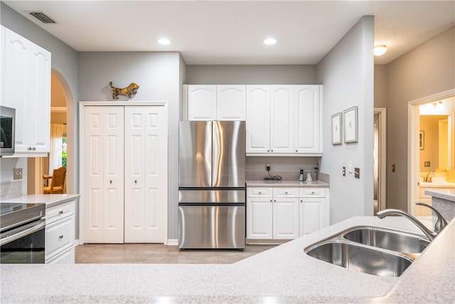 kitchen featuring white cabinets, stainless steel appliances, sink, and light tile patterned floors