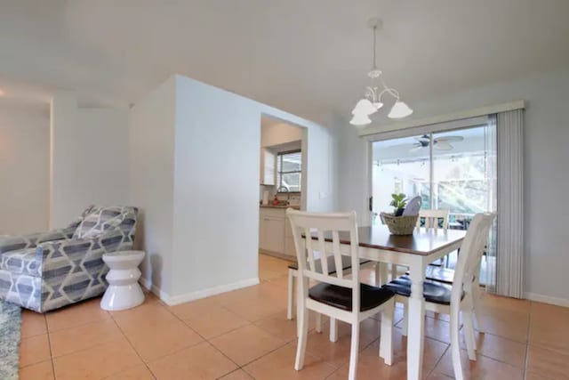 dining area featuring light tile patterned floors, baseboards, and a notable chandelier