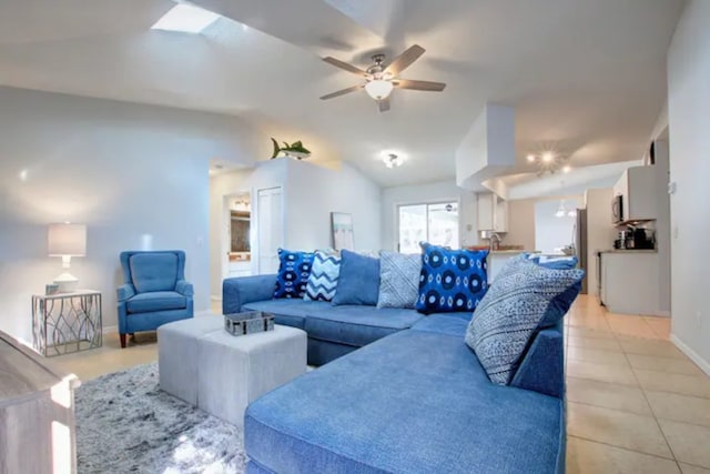 living area with light tile patterned floors, baseboards, lofted ceiling, and ceiling fan