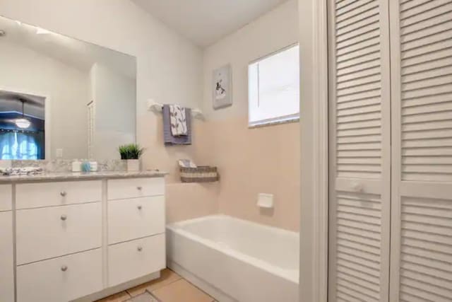 bathroom featuring tile patterned floors, a closet, vanity, and a tub to relax in