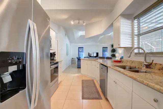 kitchen featuring light tile patterned floors, a sink, appliances with stainless steel finishes, white cabinetry, and open floor plan