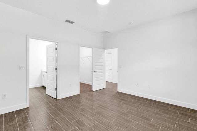 8050 96th Ave, Vero Beach, FL 32967 - unfurnished bedroom featuring wood finished floors, a walk in closet, baseboards, and a closet