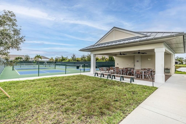 view of property's community with a lawn and tennis court