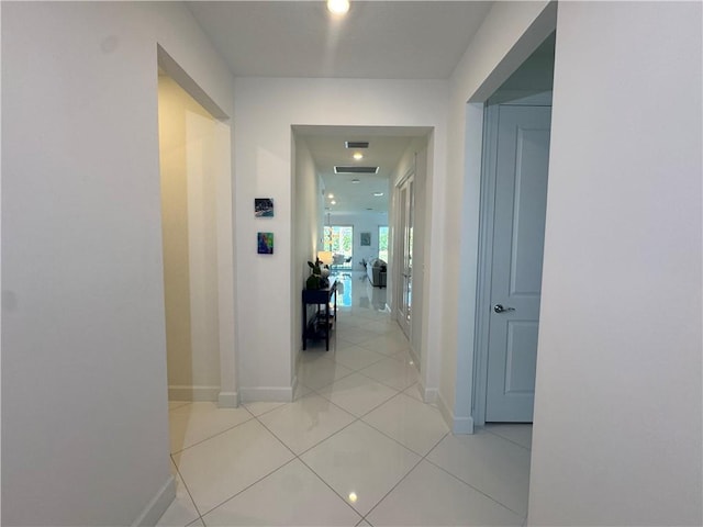 hall featuring light tile patterned floors, visible vents, and baseboards