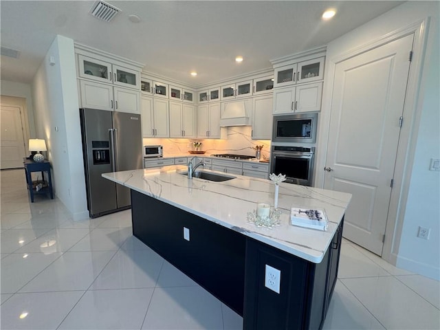 kitchen featuring light tile patterned flooring, a sink, appliances with stainless steel finishes, custom exhaust hood, and tasteful backsplash