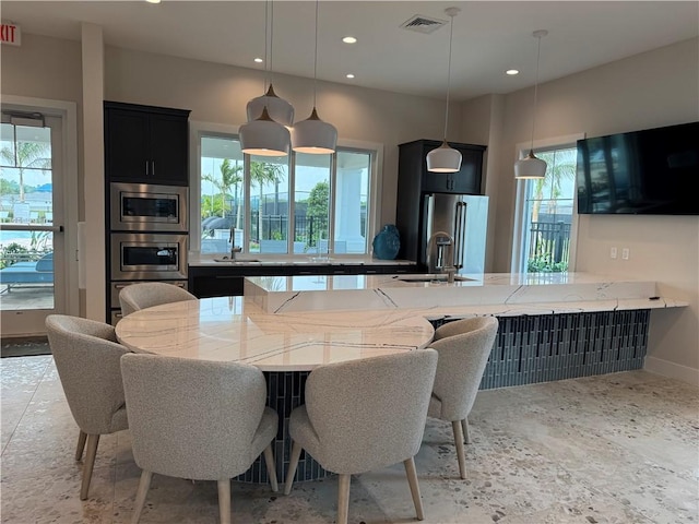 kitchen featuring a sink, stainless steel appliances, dark cabinetry, and recessed lighting