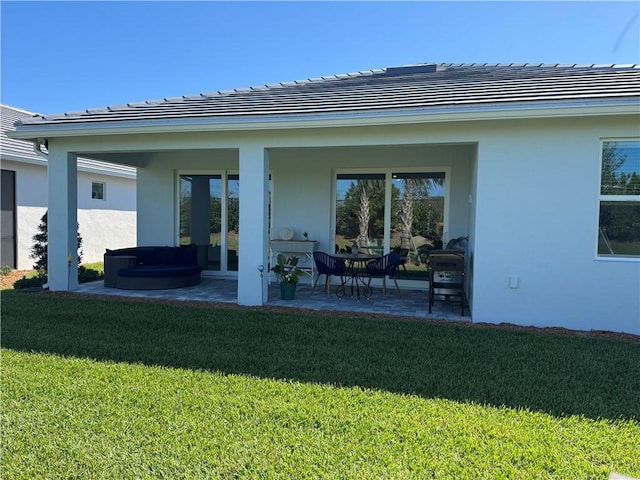 back of property featuring a yard, a patio area, and stucco siding