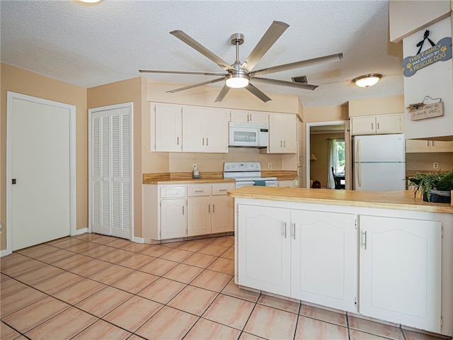 kitchen featuring a textured ceiling, white cabinetry, light tile patterned floors, and white appliances