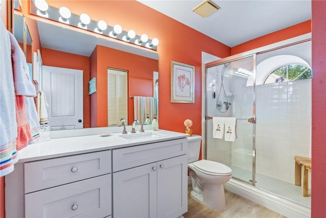 bathroom featuring hardwood / wood-style floors, vanity, toilet, and walk in shower