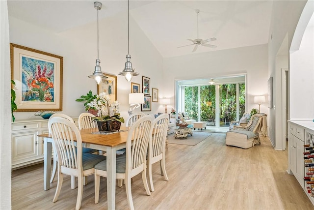 dining space featuring ceiling fan, light wood-type flooring, and high vaulted ceiling