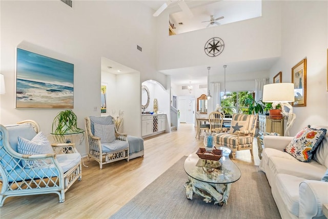 living room with ceiling fan, light hardwood / wood-style flooring, and a high ceiling