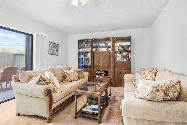 living room with ceiling fan, a textured ceiling, and carpet