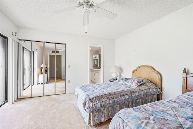 carpeted bedroom with ensuite bathroom, ceiling fan, a textured ceiling, and a closet