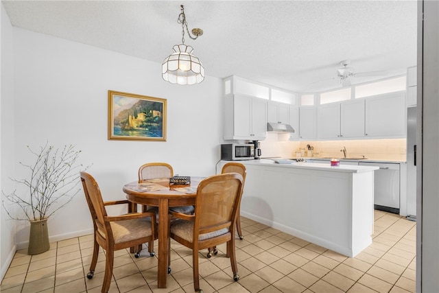 tiled dining space featuring ceiling fan, a textured ceiling, and sink