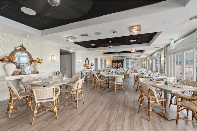 dining space featuring a tray ceiling, french doors, and light hardwood / wood-style floors