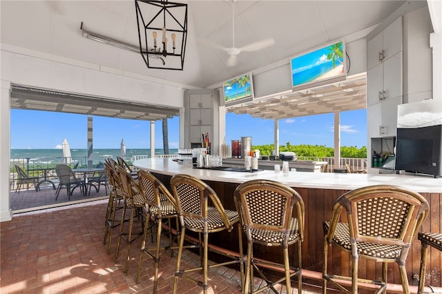 interior space featuring indoor bar, a water view, an inviting chandelier, and plenty of natural light