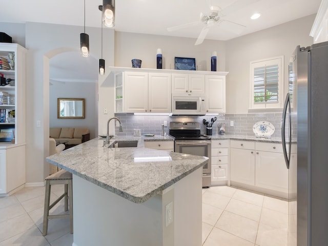 kitchen with a kitchen breakfast bar, sink, kitchen peninsula, appliances with stainless steel finishes, and white cabinetry