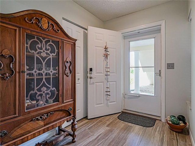 foyer entrance featuring a textured ceiling and light wood finished floors