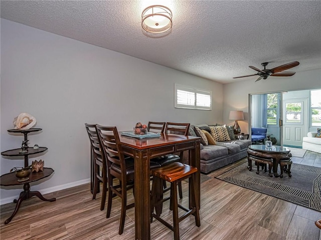 dining room with baseboards, a textured ceiling, and light wood-style floors