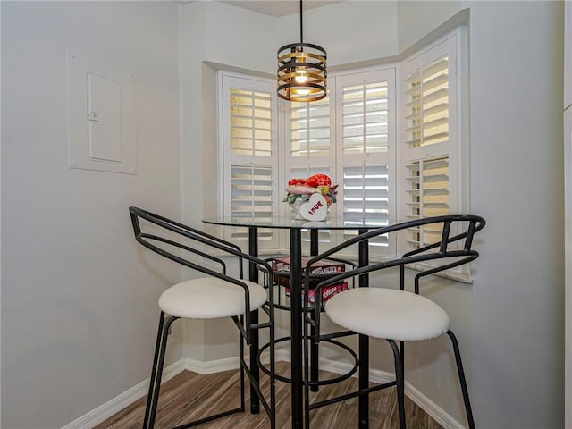 dining space featuring electric panel, baseboards, and wood finished floors