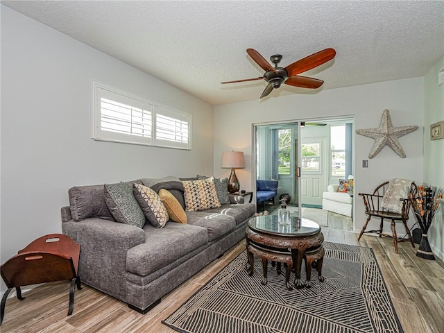 living area with a textured ceiling, ceiling fan, and wood finished floors