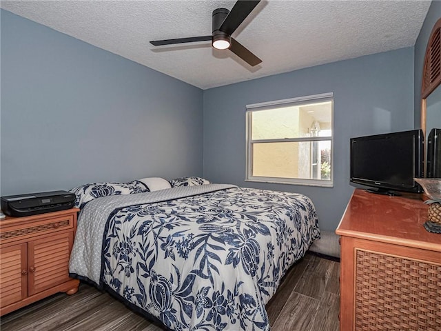 bedroom with a textured ceiling, a ceiling fan, and dark wood-style flooring