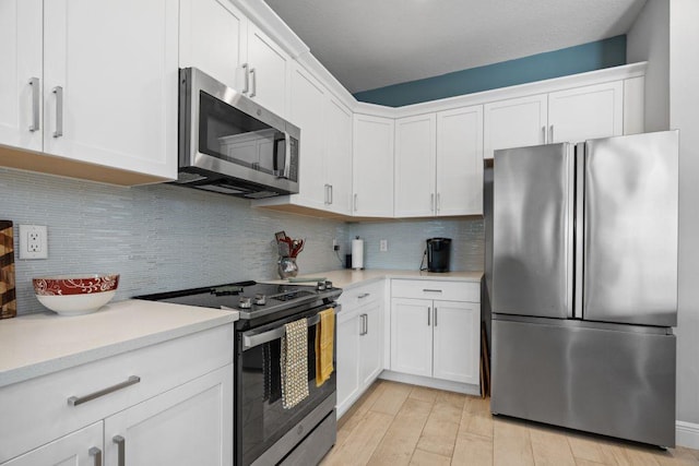 kitchen featuring decorative backsplash, light hardwood / wood-style floors, white cabinetry, and stainless steel appliances