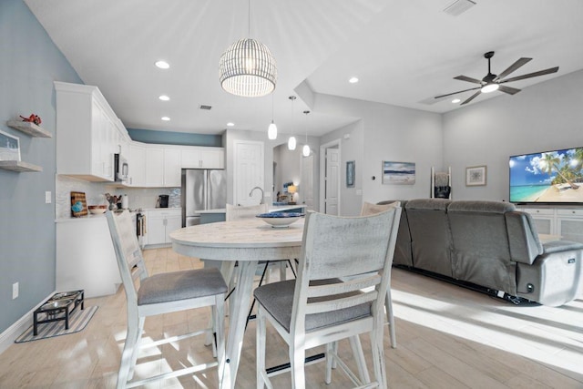 dining space with ceiling fan, sink, and light hardwood / wood-style flooring