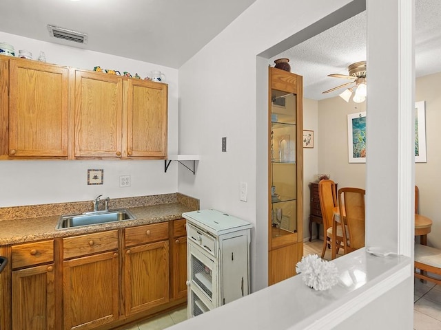 2800 Indian River Blvd Unit 2S, Vero Beach, FL 32960 - kitchen with a sink, a ceiling fan, light tile patterned floors, brown cabinetry, and a textured ceiling