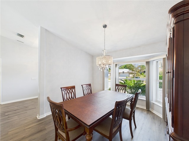 dining space featuring a chandelier, visible vents, baseboards, and wood finished floors