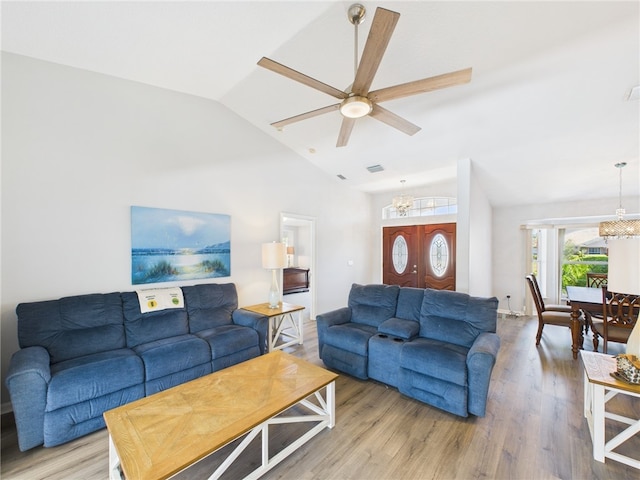 living room featuring vaulted ceiling, ceiling fan with notable chandelier, visible vents, and wood finished floors