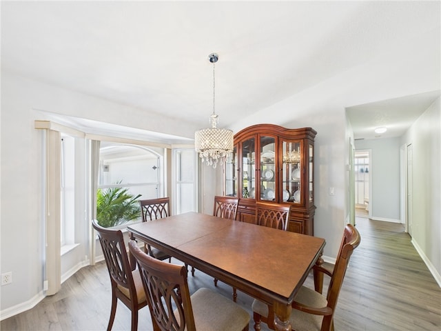 dining area featuring an inviting chandelier, light wood-style floors, and baseboards