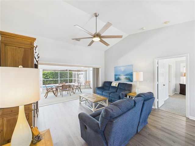 living area with a ceiling fan, lofted ceiling, wood finished floors, and baseboards