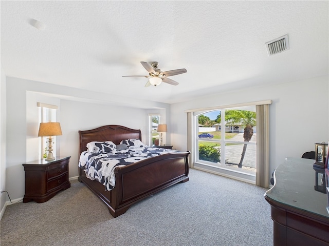 bedroom featuring visible vents, a textured ceiling, carpet flooring, and a ceiling fan