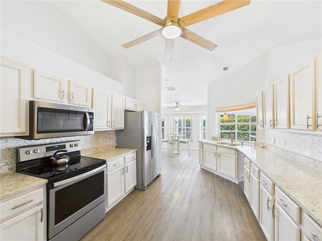 kitchen featuring decorative backsplash, light wood-style flooring, high vaulted ceiling, and stainless steel appliances