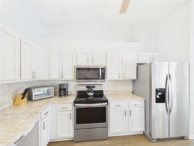 kitchen featuring a toaster, vaulted ceiling, light wood-style flooring, stainless steel appliances, and white cabinetry