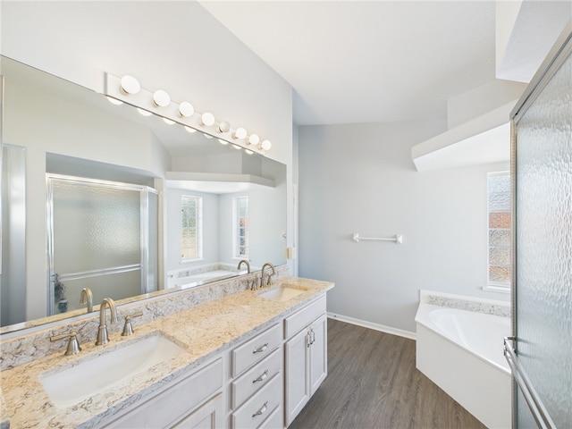 full bathroom with double vanity, a bath, wood finished floors, and a sink