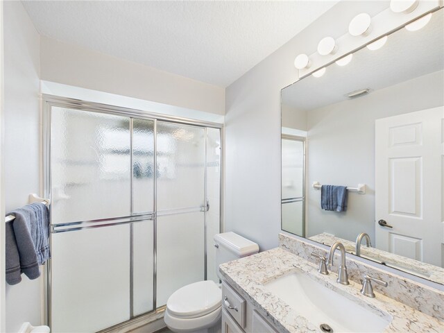 bathroom with visible vents, toilet, a stall shower, a textured ceiling, and vanity