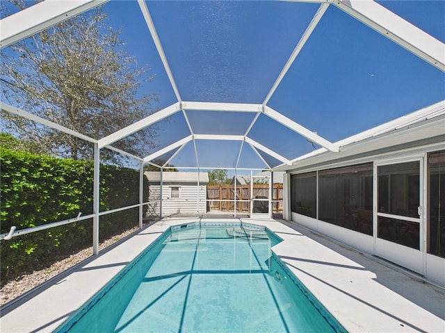 view of swimming pool with glass enclosure, a patio, a fenced in pool, and a fenced backyard