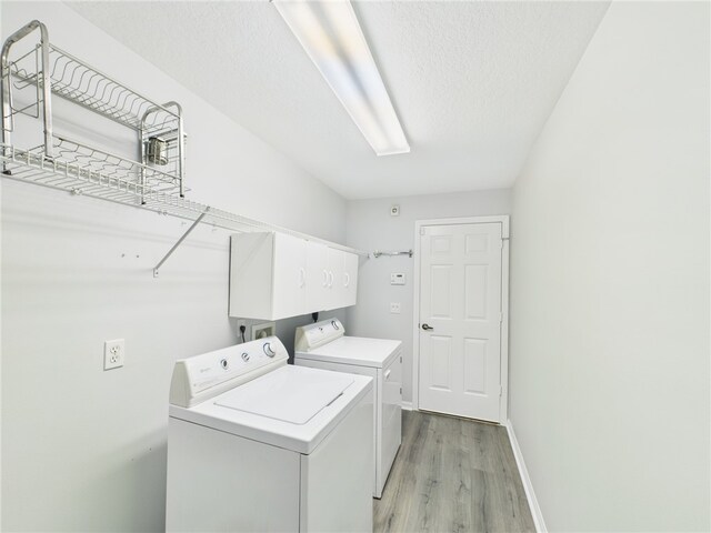 washroom featuring baseboards, laundry area, light wood-style flooring, separate washer and dryer, and a textured ceiling