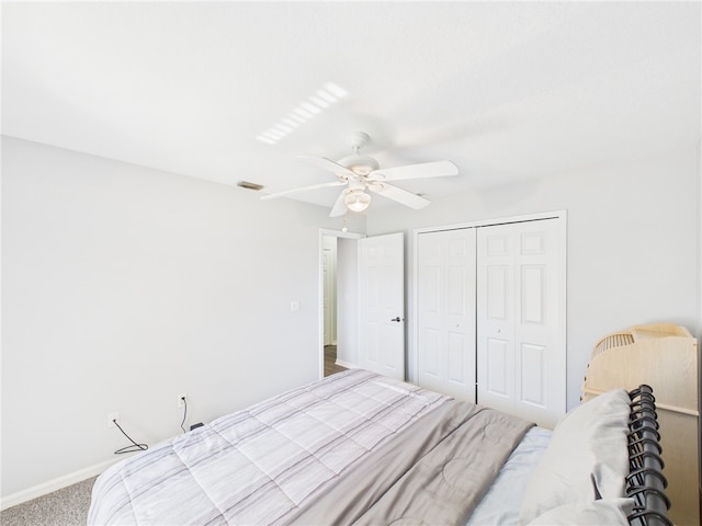 carpeted bedroom with visible vents, baseboards, a closet, and a ceiling fan