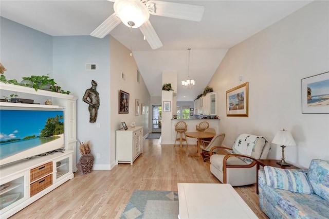 living room featuring ceiling fan with notable chandelier, vaulted ceiling, and light hardwood / wood-style floors