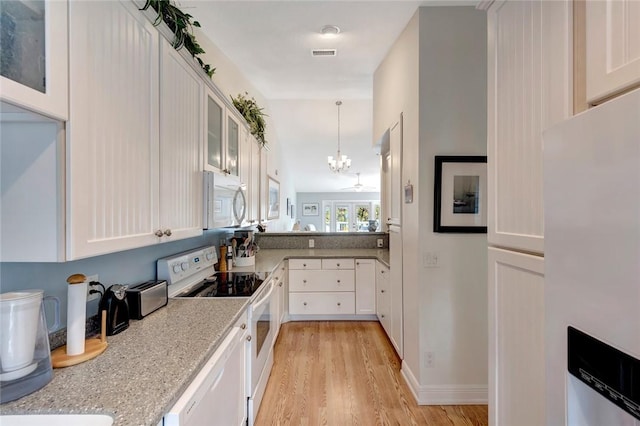 kitchen featuring light stone counters, white appliances, and white cabinets